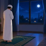 A man reciting Tahajjud dua in a dimly lit room facing a night sky window